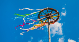 Wooden wheel with colorful ribbons on blue sky background. Slavic celebration of Midsummer